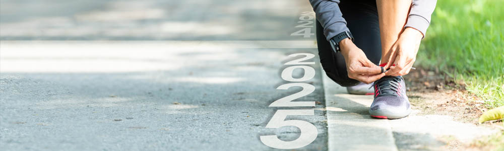 Close-up of person tying their shoe on a road, with the numbers 2025 beside them